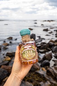 Hand holding up Crab Trapper Whiskey at the beach